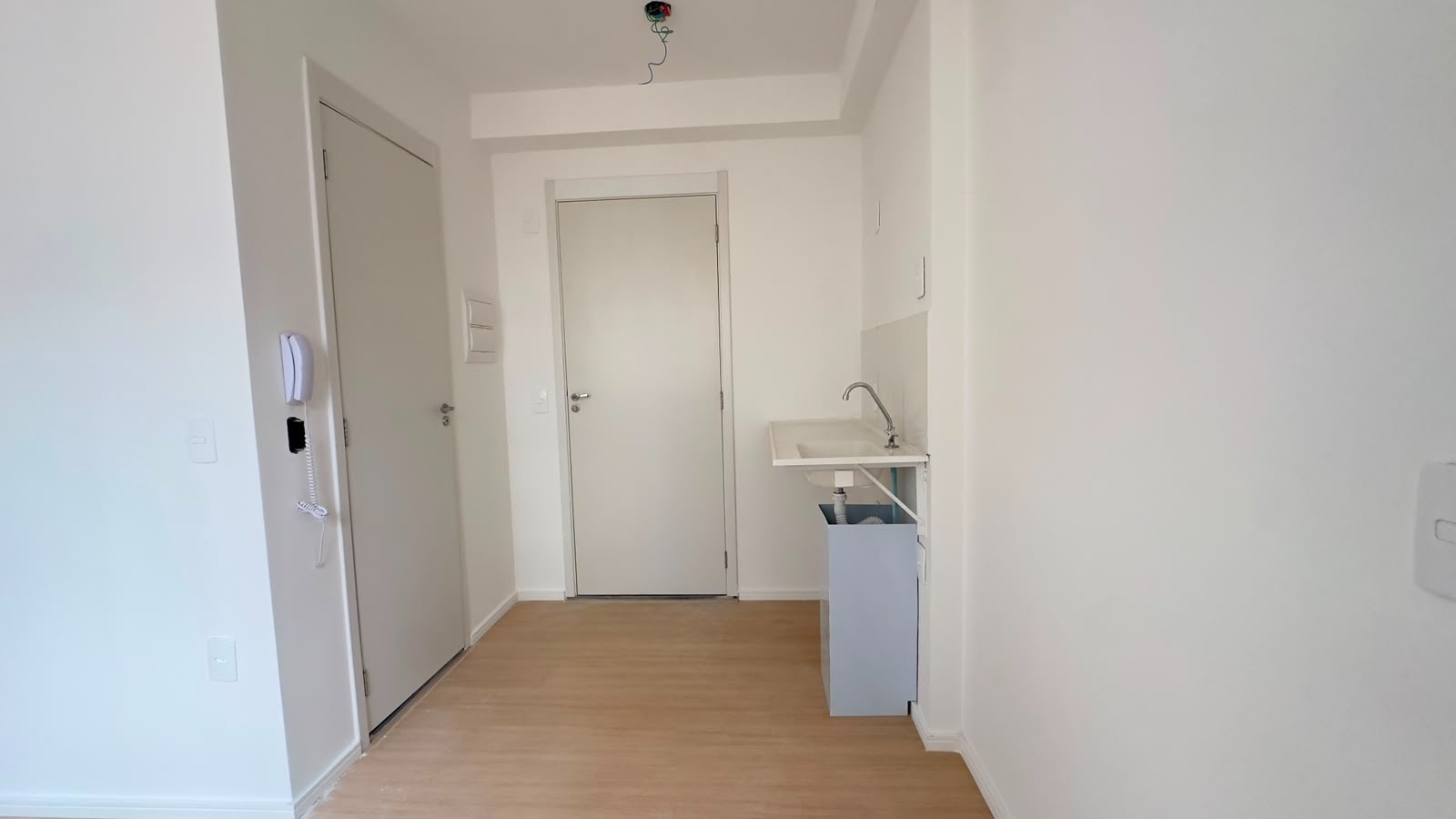 Vista da sala para a porta de saida e cozinha.