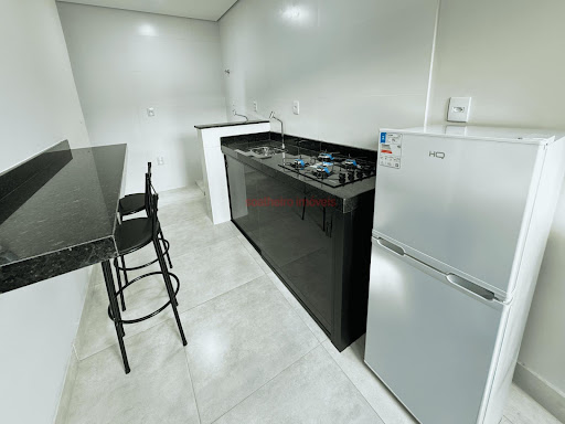 Cozinha com cooktop, geladeira e banquetas