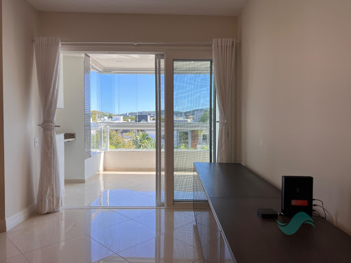 Sala de estar integrada do apartamento em Jurerê Internacional, com piso de porcelanato