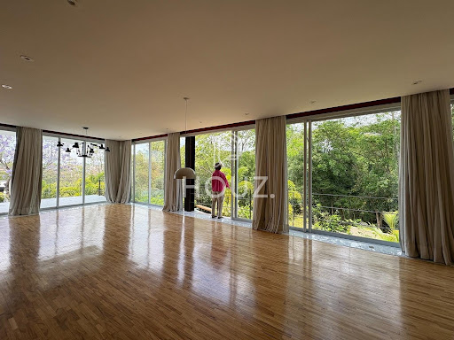 Sala de estar toda envidraçada, com vista para a mata
