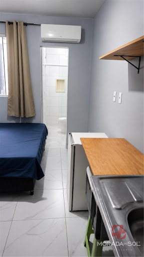Ambiente mobiliado com cama, cozinha e ar-condicionado