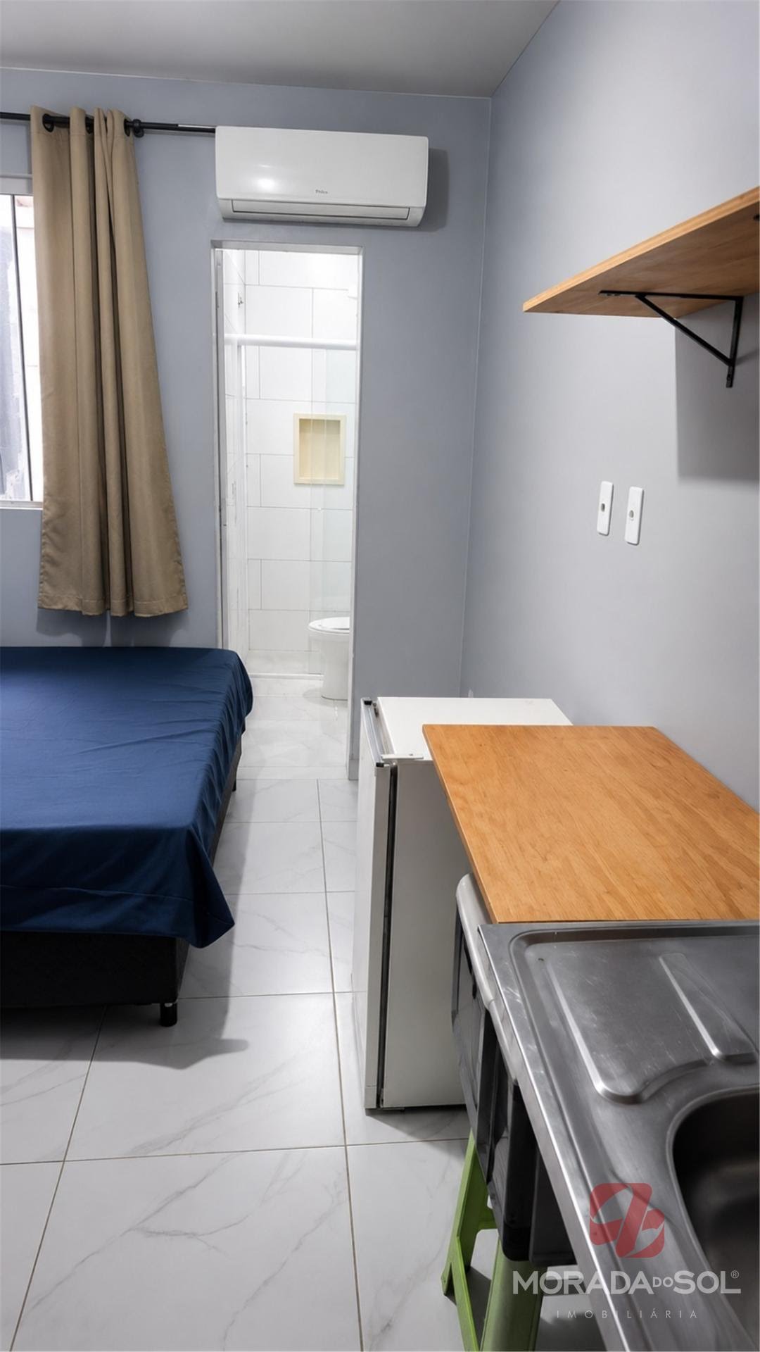 Ambiente mobiliado com cama, cozinha e ar-condicionado