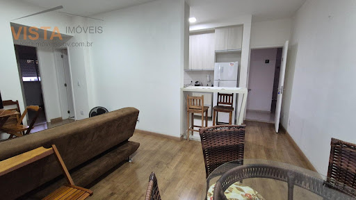 Sala com sofá, TV, mesa com cadeiras, bancos