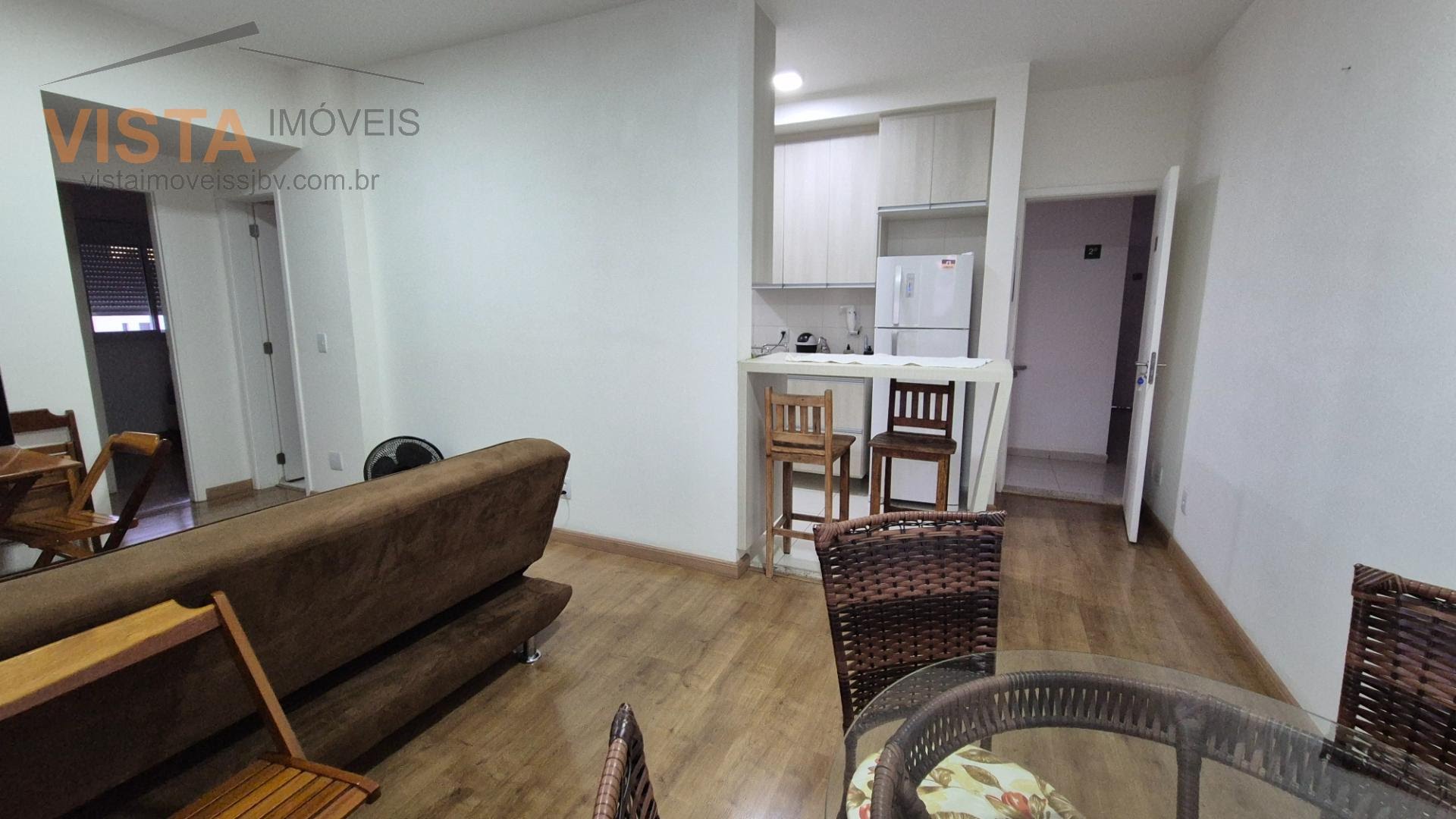 Sala com sofá, TV, mesa com cadeiras, bancos